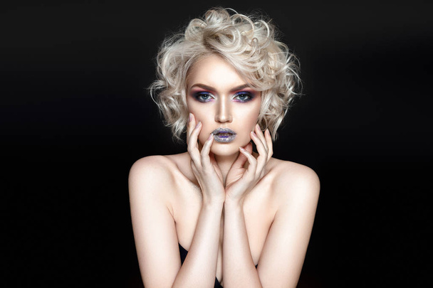 Young curly model with fashionable glossy makeup posing on black background - Photo, image