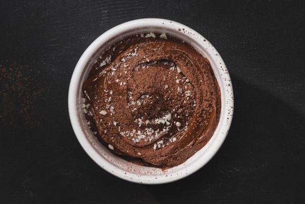 top view of bowl with chocolate dessert on black table - Zdjęcie, obraz