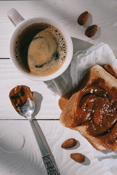 top view of toast bread with chocolate and cup of coffee on white wooden table - Foto, Bild