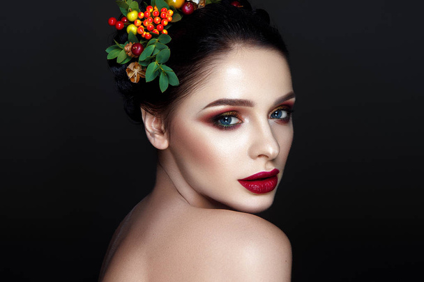 Portrait of young brunette model with fashionable red lips makeup and wreath with leaves and berries  - Photo, image