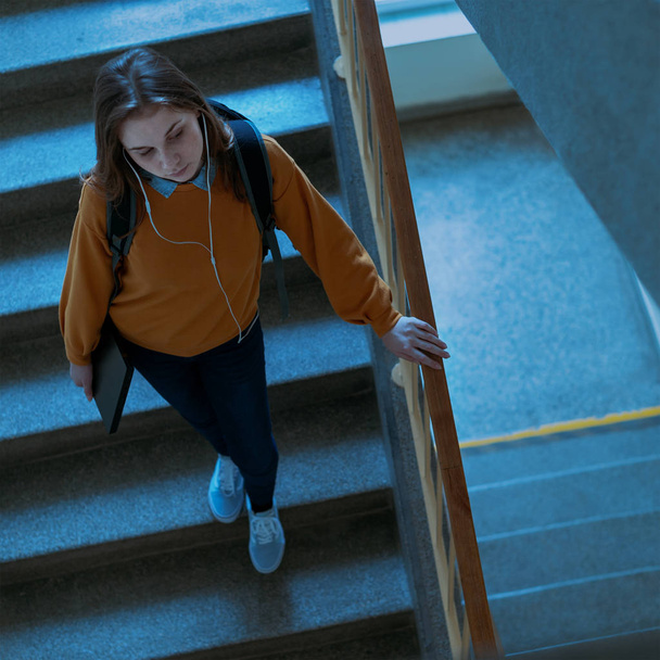 Young depressed lonely female college student walking down the stairs at her school, looking down. Education, Bullying, Depression concept. - Foto, Imagen
