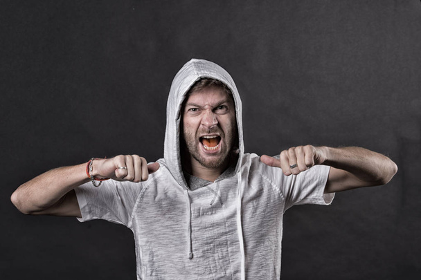 Angry man with beard show fists. Bearded man wear hood. Fashion model in hoodie tshirt. Active lifestyle and health activity. Fashion style and trend concept, vintage filter - 写真・画像