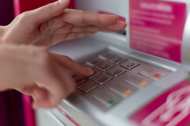 Közelről a női kéz belépő PIN pass kódot ATM Bank gép billentyűzetét, ő elrejti azt a másik kezét biztonsági okokból - Fotó, kép
