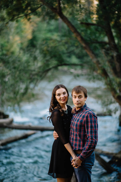 Beautiful young couple sitting on a rock near the river. Family values, love, happiness concept - Φωτογραφία, εικόνα