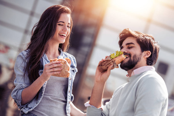 Feliz pareja joven divirtiéndose al aire libre y comiendo
  - Foto, Imagen
