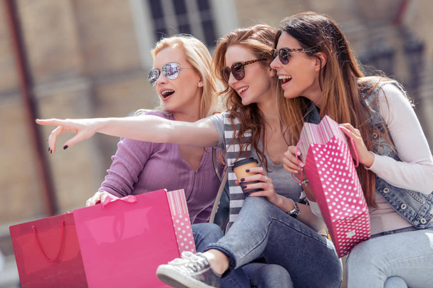 drei junge Frauen mit Einkaufstüten spazieren nach dem Einkaufen durch die Stadt - Foto, Bild