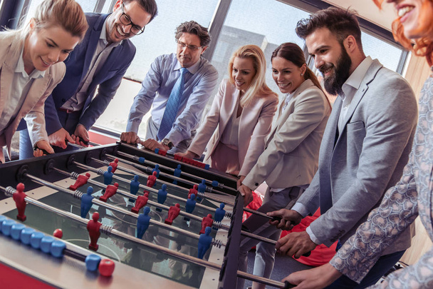Gente de negocios pasando tiempo juntos y jugando al futbolín en la oficina moderna
 - Foto, Imagen