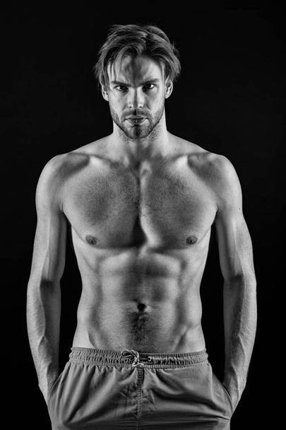 Man athlete with fit body. Sportsman with six pack and ab muscles. Macho with sexy torso and chest. Training and workout activity in gym. Sport or fitness and bodycare concept, black and white - Foto, afbeelding