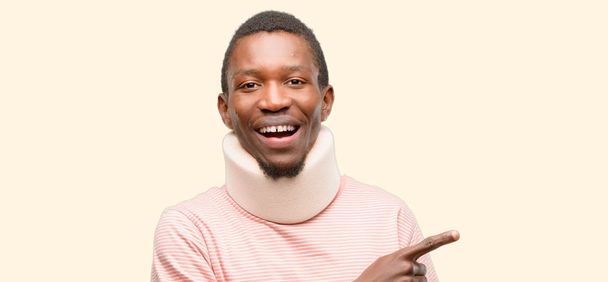 Injured african black man wearing neck brace pointing away side with finger - Photo, Image