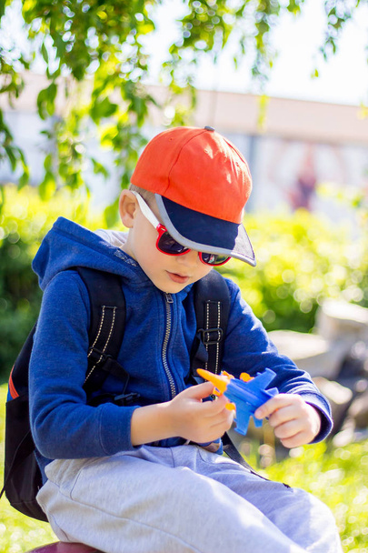 Мальчика в стильной одежде играет игрушечный самолет
 - Фото, изображение