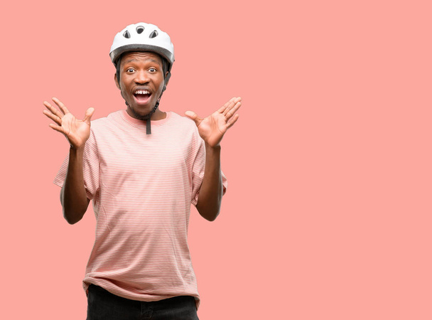 schwarzer Mann mit Fahrradhelm glücklich und überrascht jubelnd mit Wow-Geste - Foto, Bild