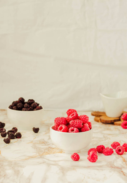 Raw raspberries and wild black, blackberries in white cups. Ligh - Fotoğraf, Görsel