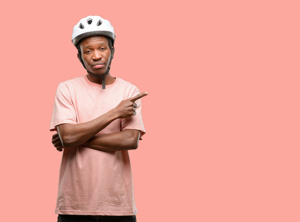 Black man wearing bike helmet pointing away side with finger - Photo, Image