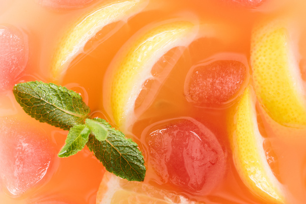 close up view of fresh cocktail with mint, ice cubes and lemon pieces background - Photo, Image