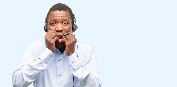 Hombre negro consultor de call center aterrorizado y nervioso expresando ansiedad y gesto de pánico, abrumado
 - Foto, imagen