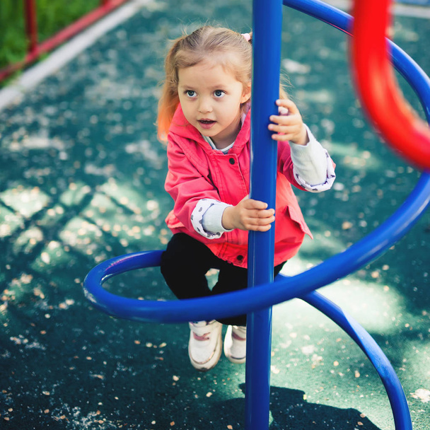 Climbing little girl at playground. Playground outdoor in summer time - Fotografie, Obrázek