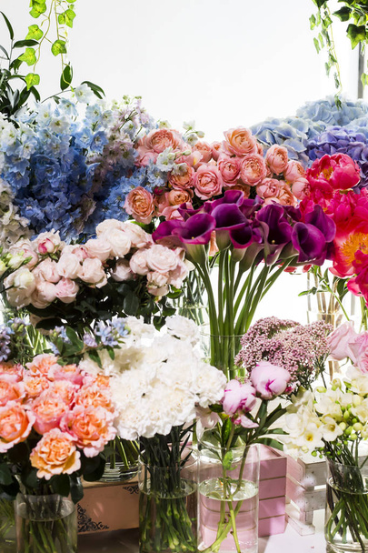 Calla ιώδη λουλούδια σε ένα βάζο στον πάγκο σε ένα κατάστημα λουλούδι ανάμεσα σε άλλα πολύχρωμα και ποικίλα λουλούδια - Φωτογραφία, εικόνα
