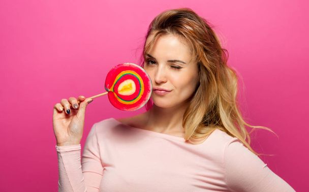Beautiful young woman with big lollipop on pink background - Foto, Imagem
