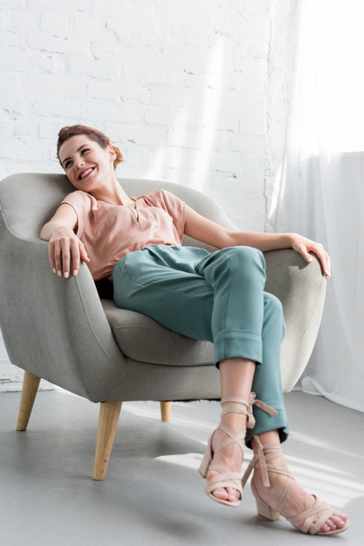 glückliche junge Frau entspannt sich zu Hause im Sessel - Foto, Bild