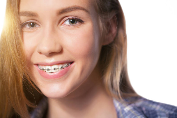 Beautiful young blondie girl showing her dental braces isolated on white - Photo, Image