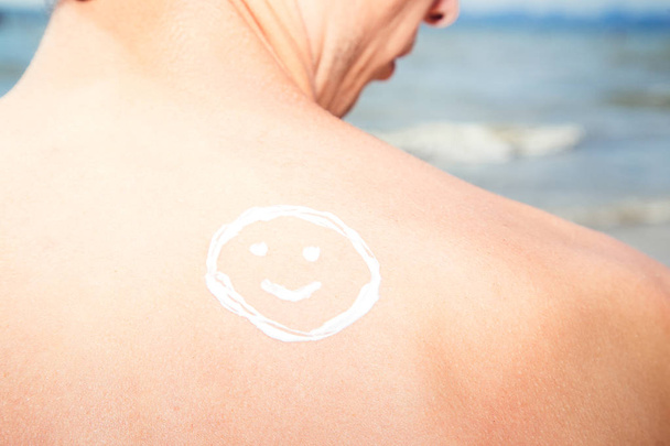 Lotion homme avec écran solaire smiley au-dessus du fond de la mer
 - Photo, image