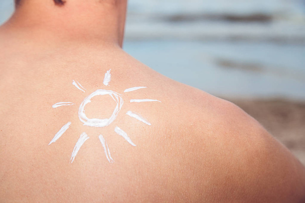 Güneş deniz arka plan üzerinde güneş koruyucu losyon adamla - Fotoğraf, Görsel