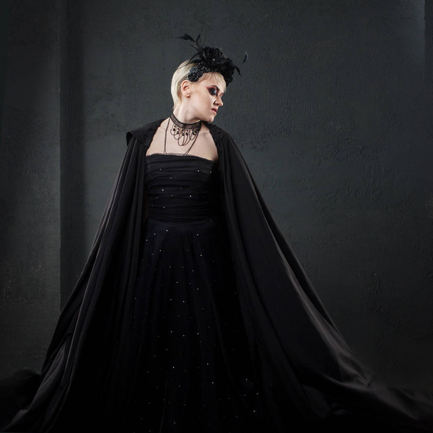 Retrato de uma mulher loira gótica elegante. Menina em coroa de flores pretas e capa preta
 - Foto, Imagem