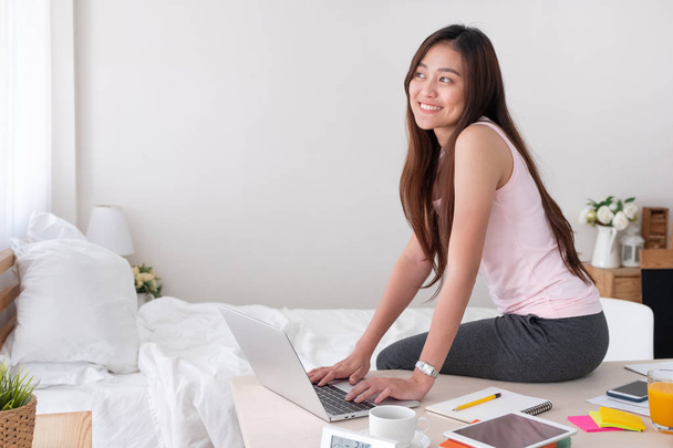 Asian female freelancer wear vest shirt typing on laptop on tabl - Photo, Image