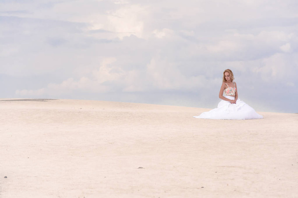дівчина в весільній сукні в піщаних барбанах біжить на піску нареченої
 - Фото, зображення