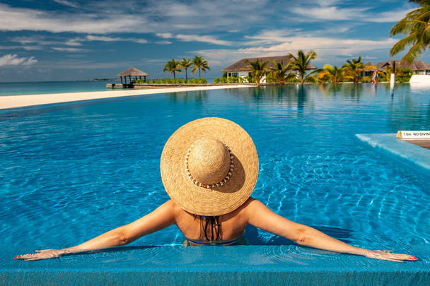 Donna con cappello da sole in piscina in spiaggia alle Maldive
 - Foto, immagini