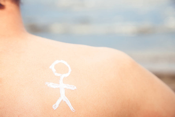 Man van de lotion met zonnebrandcrème met een mannetje op de pagina van de zee - Foto, afbeelding