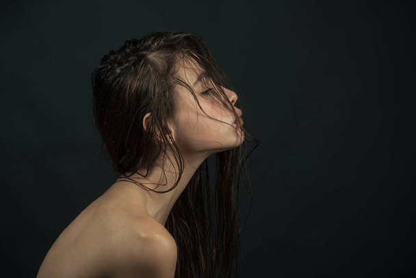 Serious looking female model with dark hair on grey background, copy space - Fotografie, Obrázek