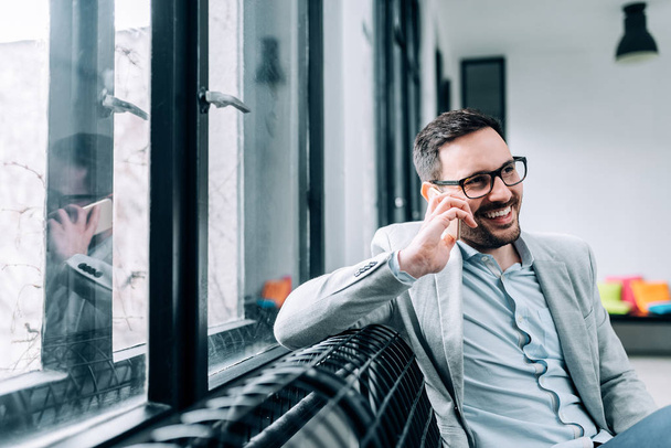 Portrait of successful businessman talking on smartphone in office  - Foto, imagen