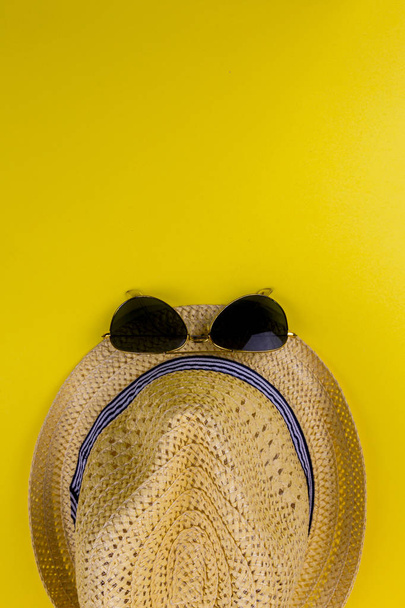 Vintage słomy kapelusz i czarne okulary przeciwsłoneczne fasion dla człowieka na żółtym tle z miejsca kopiowania, koncepcja podróży na żółtym tle. Widok z góry - Zdjęcie, obraz