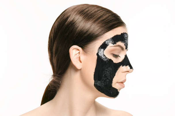 Young beautiful woman applying a mask for the face of the therapeutic black mud. Spa treatment - Φωτογραφία, εικόνα