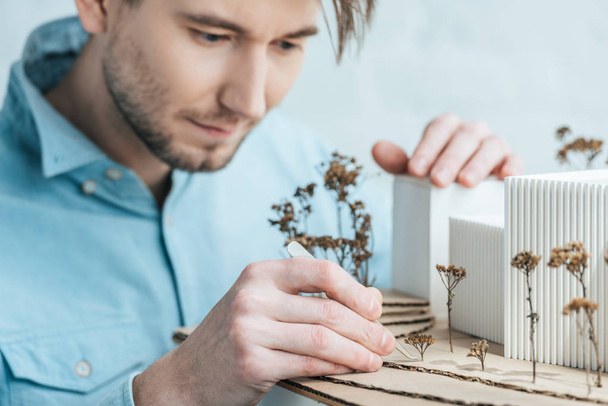 selective focus of focused architect looking at self made building model in office - Fotografie, Obrázek