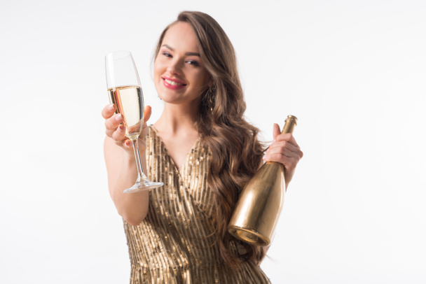 uśmiechający się atrakcyjne kobiety stojącej z butelkę i kieliszek szampana na białym tle - Zdjęcie, obraz