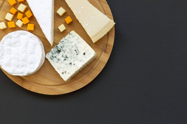 Various types of cheese on round wooden board, top view. Dark background. Copy space. Flat lay. From above. - Fotoğraf, Görsel