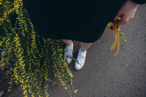 Looking down view of female legs standing by blooming wildflowers  - Zdjęcie, obraz