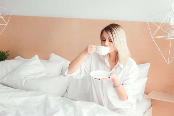 Hermosa mujer bebiendo un café sentada en su casa cama
 - Foto, imagen