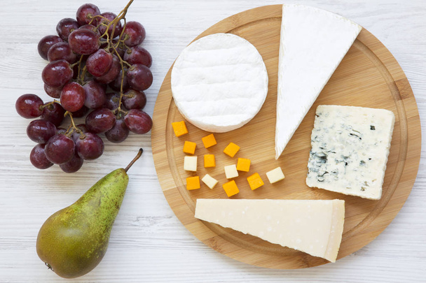 Tasting cheese with fruits on a white wooden background. Food for wine, top view. Flat lay. From above. - Photo, Image