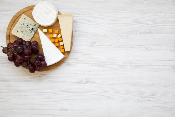 Tasting cheese with grapes on round wooden board. Food for wine, top view. Space for text. Flat lay. From above. - Photo, Image