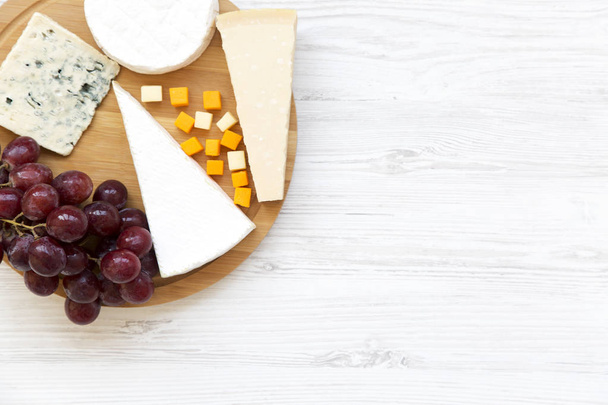 Tasting cheese with grapes on white wooden background. Food for wine, top view. Space for text. Flat lay. From above. - Photo, Image