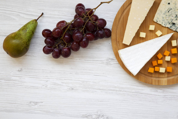 Degustação de queijo com frutas em fundo de madeira branca. Comida para vinho, espaço de cópia. Deitado. De cima, vista superior
. - Foto, Imagem