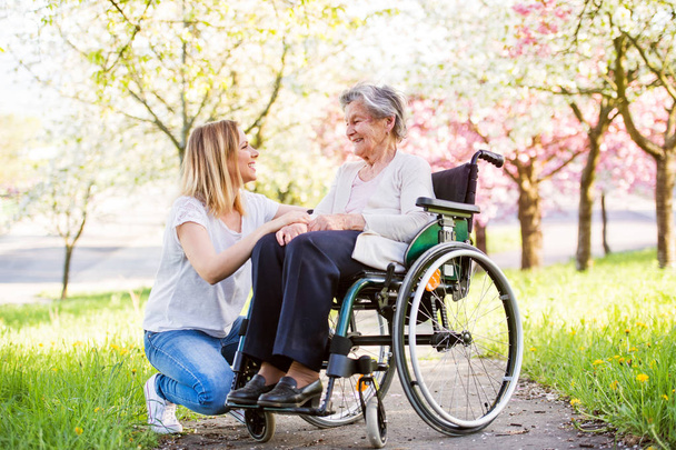 Grand-mère âgée en fauteuil roulant avec petite-fille au printemps nature
. - Photo, image