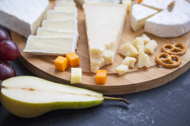 Lezzetli peynir meyveleri, simit ve ceviz koyu arka plan, closeup üzerinde. Yiyecek şarap.  - Fotoğraf, Görsel