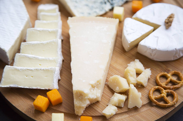 Ízletes sajt perecet és dió fából készült táblán, közelkép. Élelmiszer, bor.  - Fotó, kép