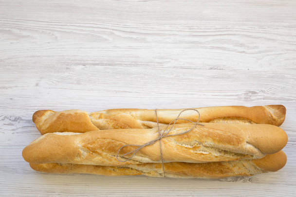 Fresh french baguettes on white wooden background, top view. Copy space. - Фото, изображение