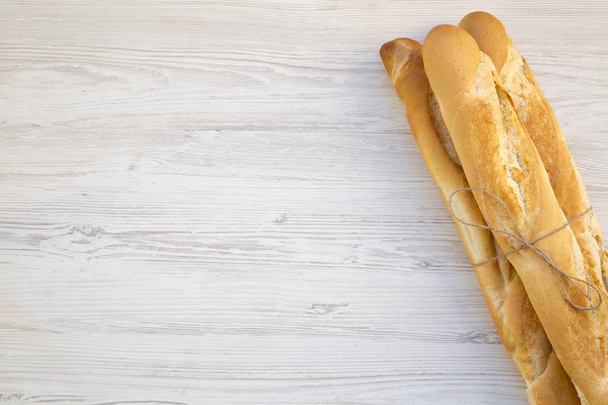 Fresh french baguettes on white wooden background, top view. Copy space. - Photo, Image