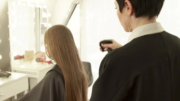 Cabeleireiro pulverização de água no cabelo longo corte de cabelo feminino no salão de cabeleireiro. Penteado feminino no salão de beleza. Cortador de cabelo trabalhando com o cliente de perto
. - Filmagem, Vídeo